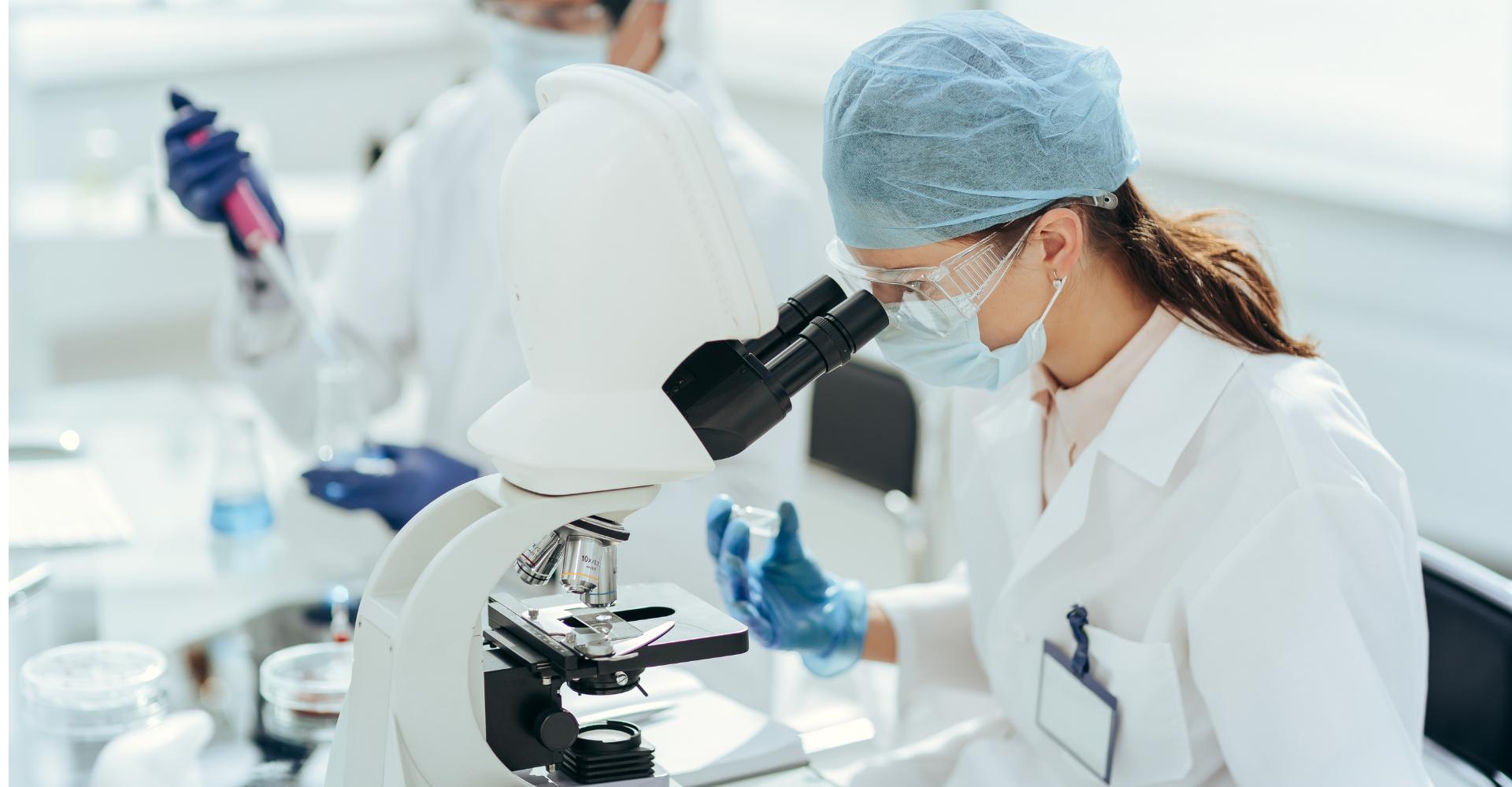 Mujer mirando a través de microscopio